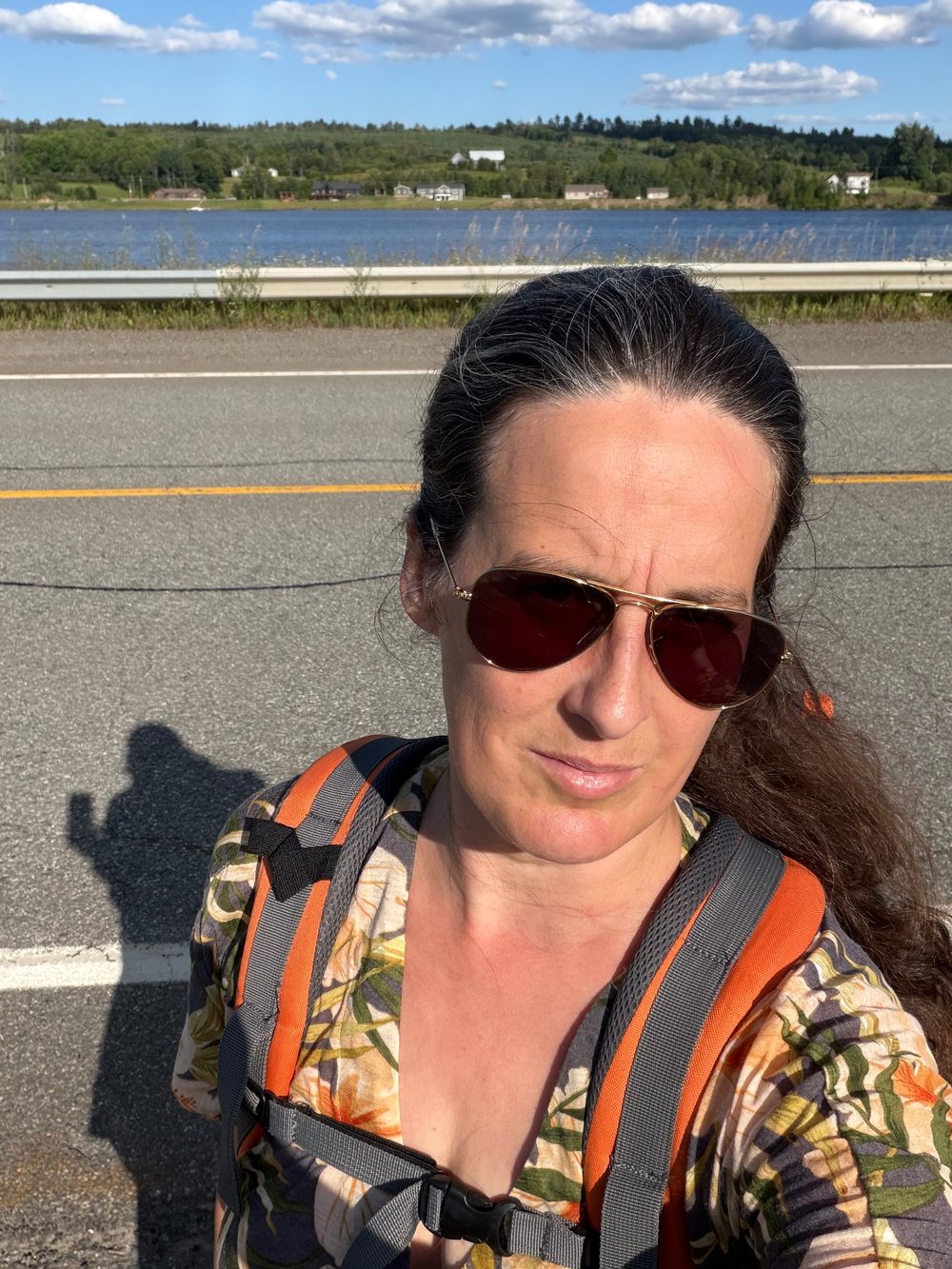 Julia training with pack on a PEI roadside, lake in the background